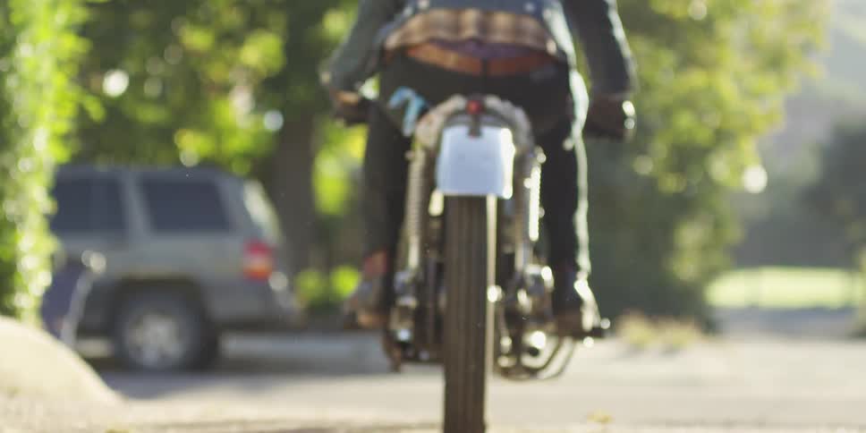 A motorcyclist rides down a sunny street