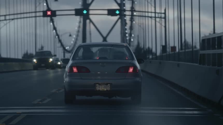 A car is moving towards the signals on the bridge