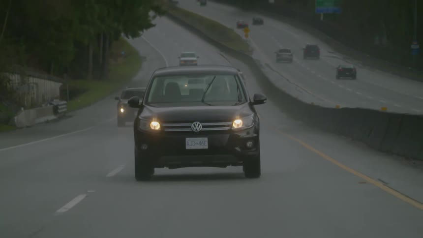 Vehicles drive down a road in the rain