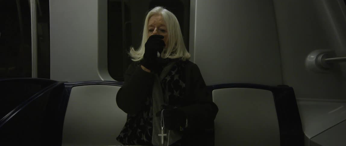 A woman sits on a subway and touches her face