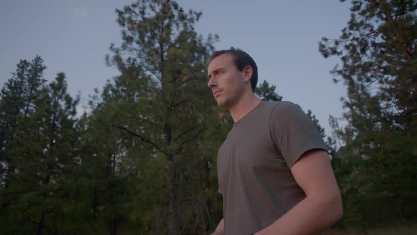 A man stands in front of trees
