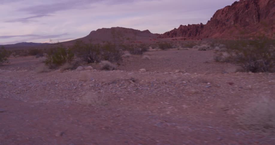Heavy clouds are hanging over a desert landscape near sunset