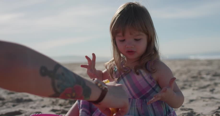 A man and young girl play on the beach
