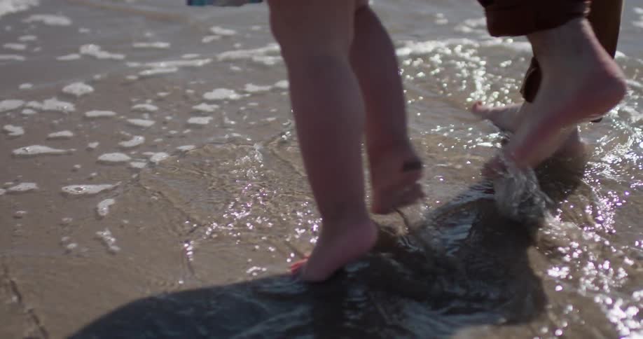 Adult and child walk on the sandy beach on a sunny day