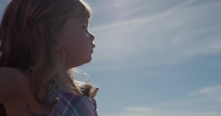 Child talks and points outside on a sunny day