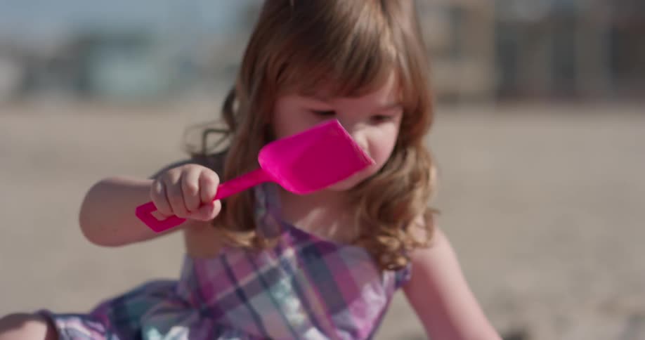A young girl plays on the beach with plastic toys
