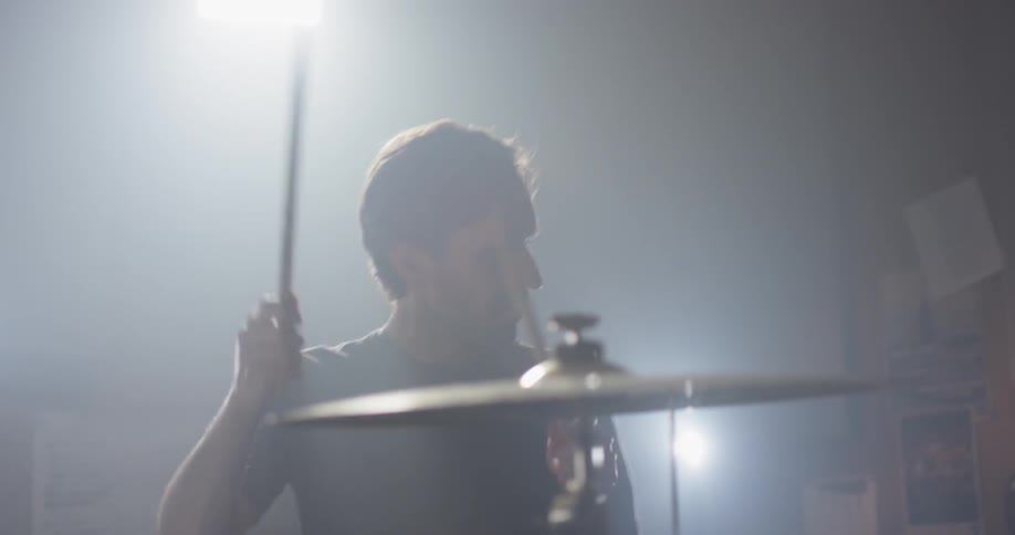 Man drums on a drum set and bobs his head