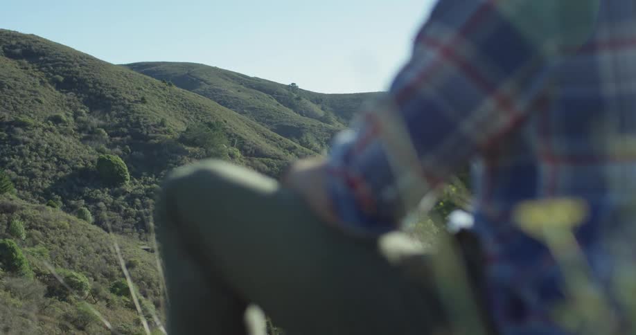 Man sits in nature near grassy hills