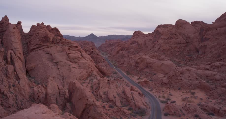 Heavy clouds are hanging over a road leading through a desert landscape