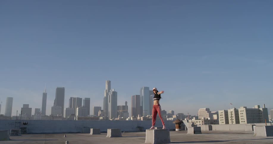 Woman dances on a rooftop in the city