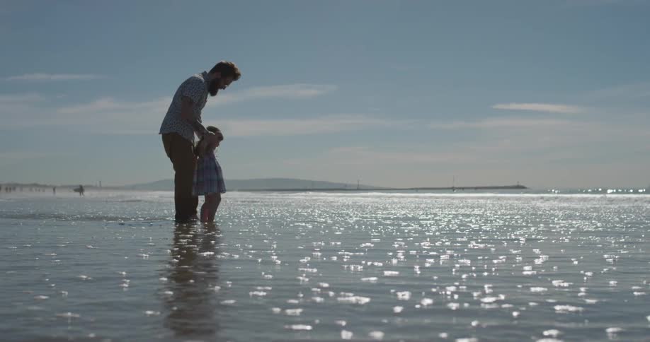 A man and young girl play as the tide rolls in