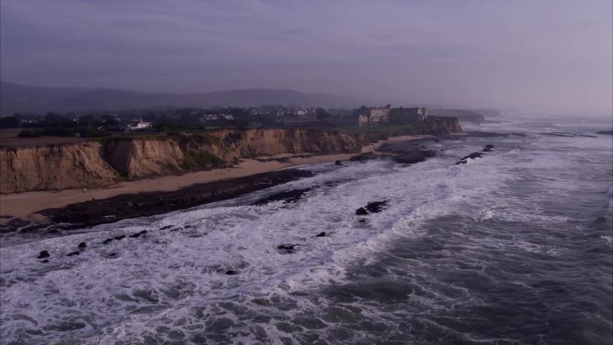 The tide rolls in towards the cliff lined shore