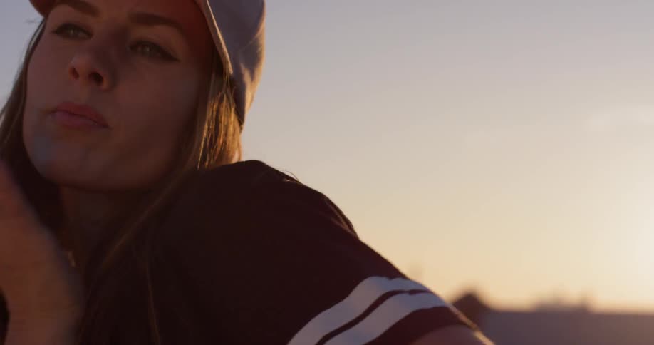 A woman in a pink hat dances on a rooftop