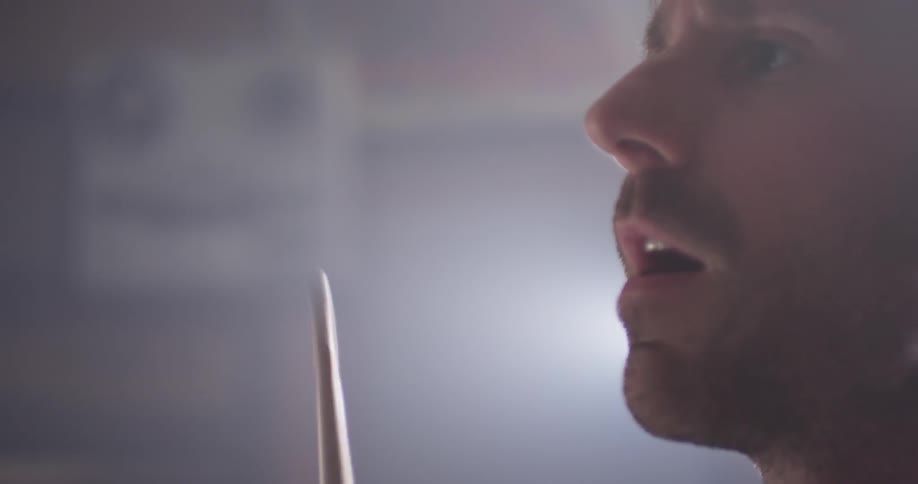 A man sings while playing drums