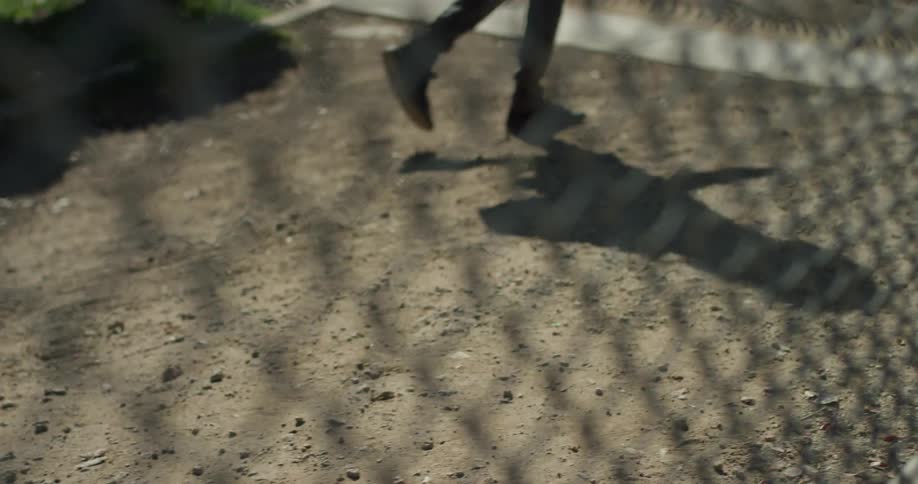 A man is walking across a vacant lot outside in daylight