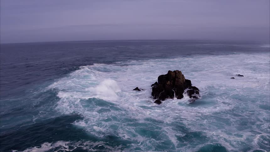 Ocean waves crash against jutting rocks