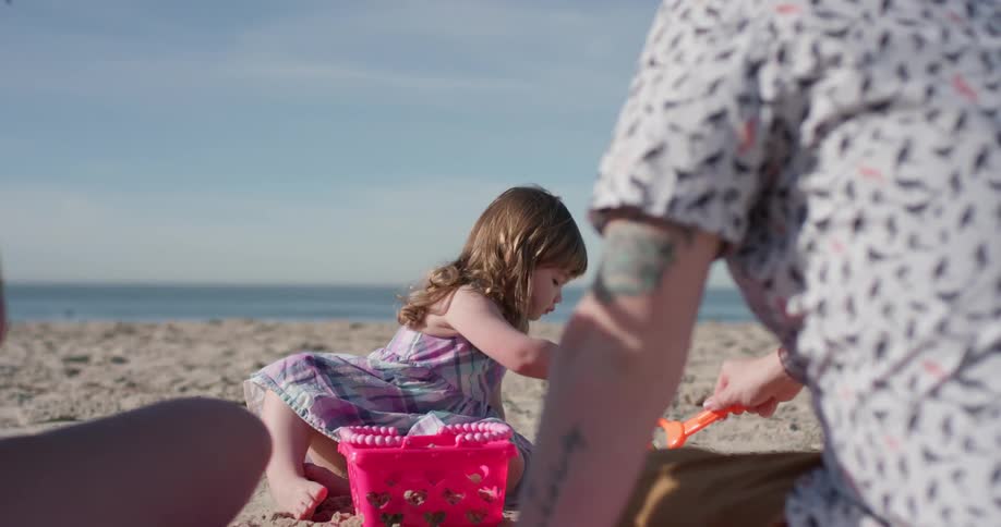 A young family plays with sand on a beach