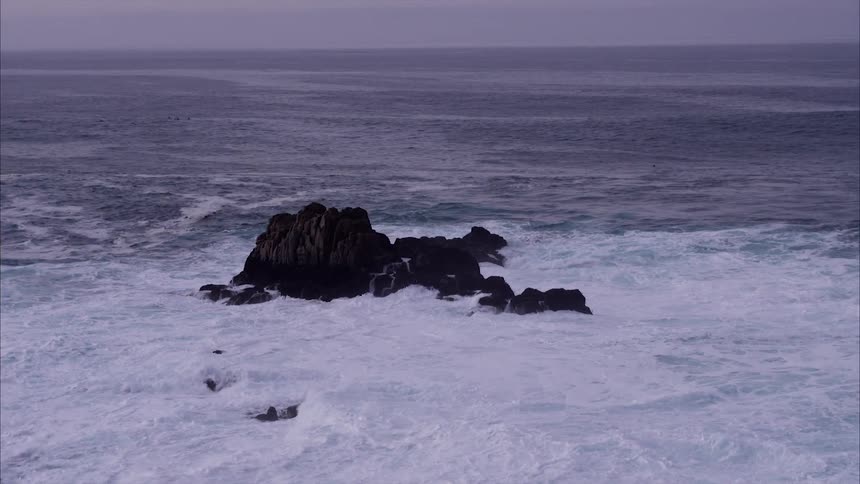 The waves crash against the rocks in the water