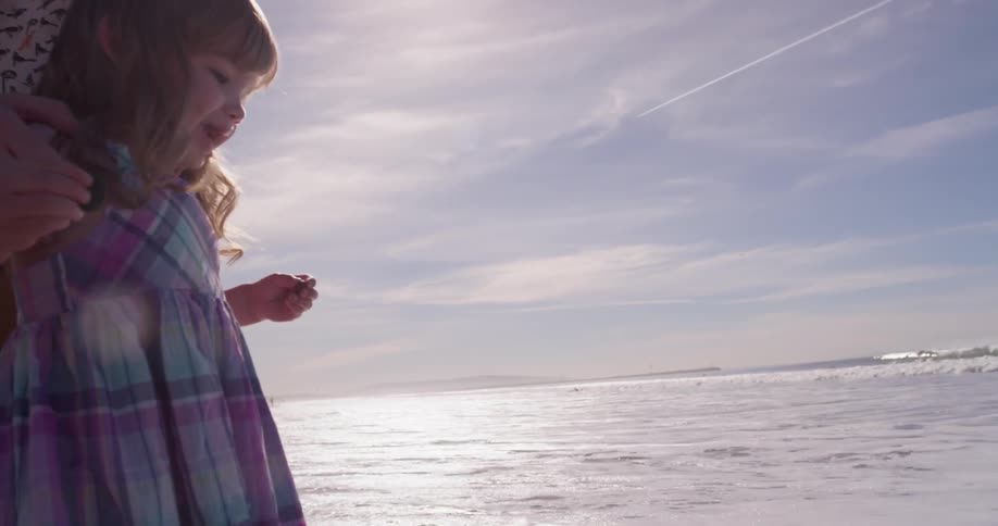 A man and young girl play on the beach