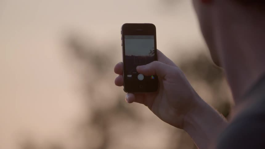 A man holding up his cell phone to take a picture
