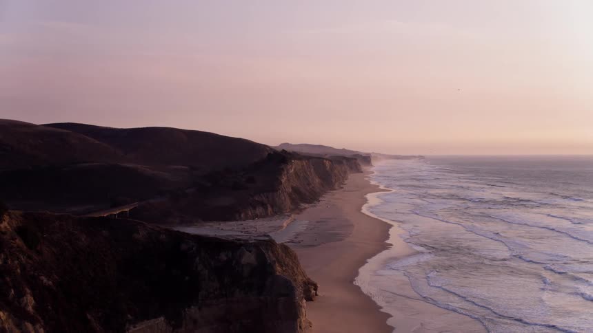 Ocean waves flow towards a shoreline at sunset