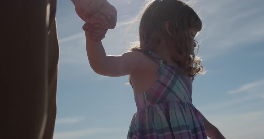A young girl holds the hand of a man and smiles