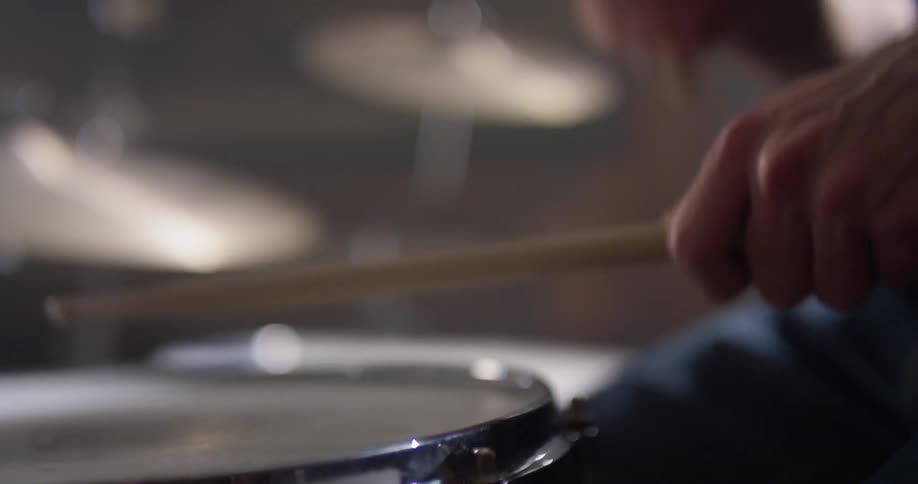 Person taps drumsticks on a snare drum