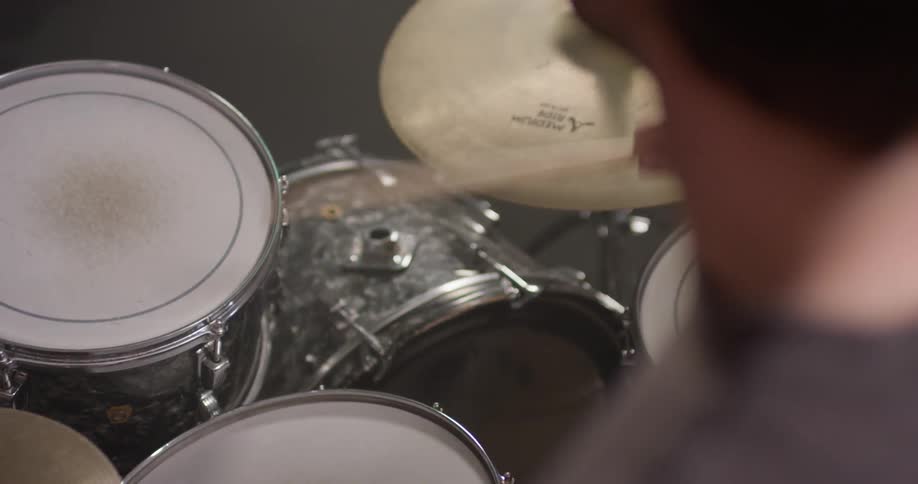 Man bobs his head and drums on a drum set