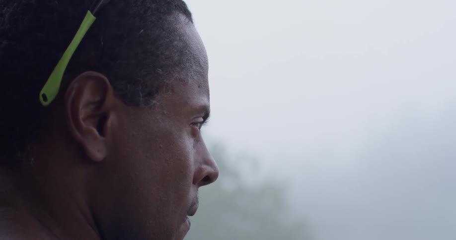 A man takes off his sunglasses outside on a foggy day