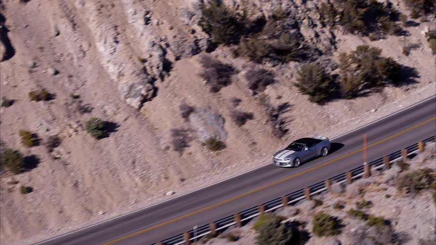 Car drives down a winding road through the mountains