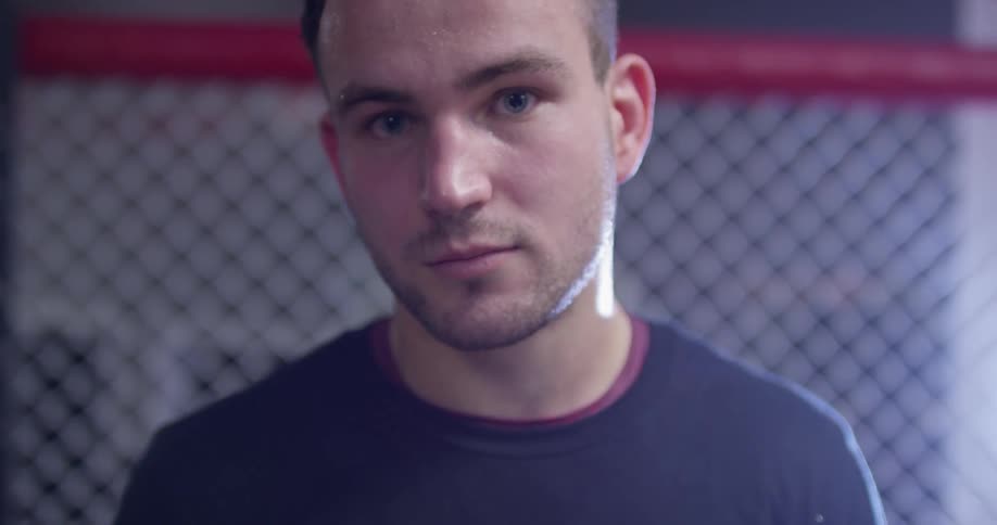 A sweaty man stands in a fighting ring