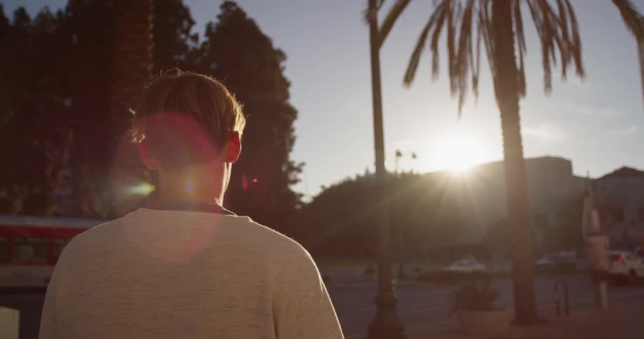 A man walks in a city at sunset