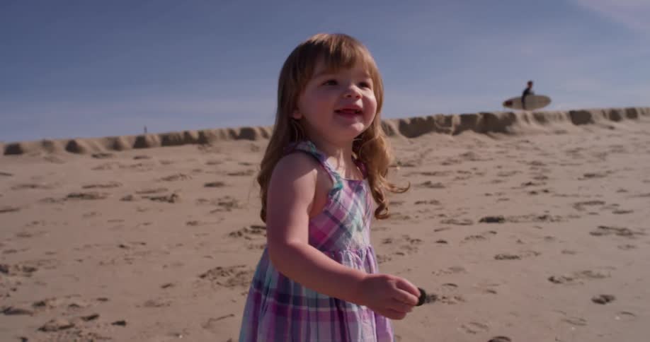 Toddler walks on the beach smiling