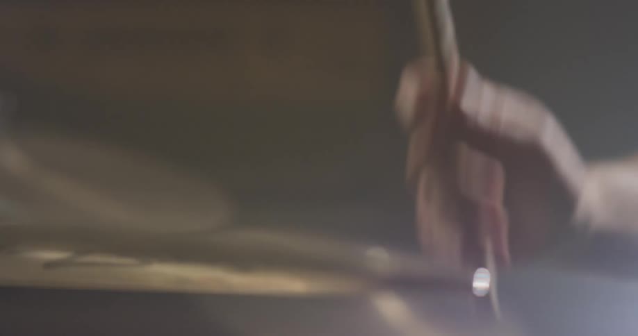 A drummer taps on a cymbal with a drumstick