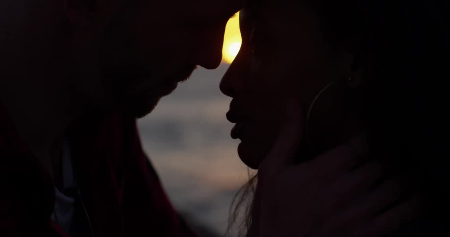 A man and woman flirt on a beach at sunset