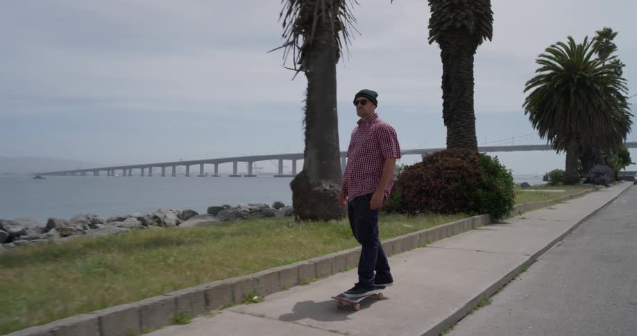 A man is skateboarding down the sidewalk