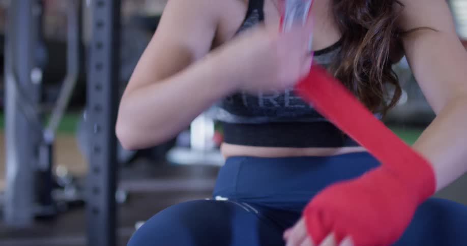 A woman wraps up her hand at the gym