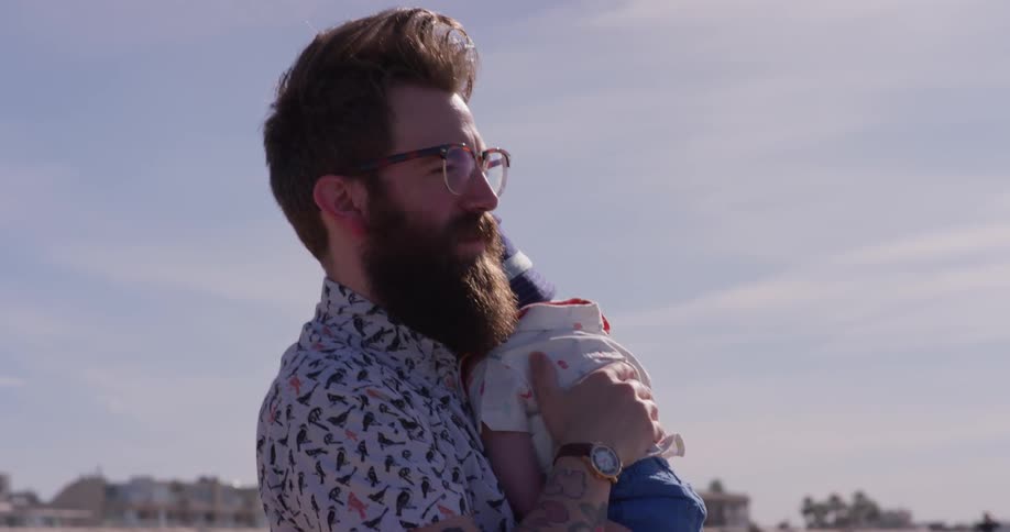 A man holds a baby on the beach