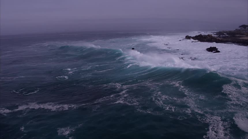 Ocean waves splash around and over rocks near shore