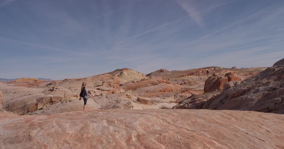 A woman walks on rocky terrain in the desert