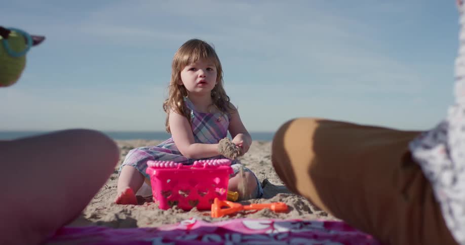 A young girl plays on the beach with plastic toys