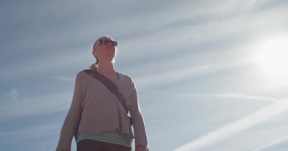 Woman walks on rocky hill on a sunny day