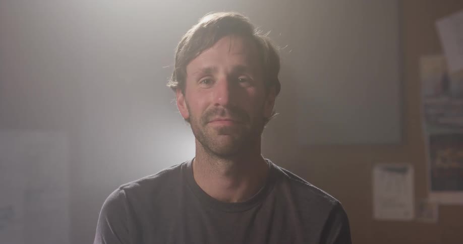 A man begins to smile as he sits