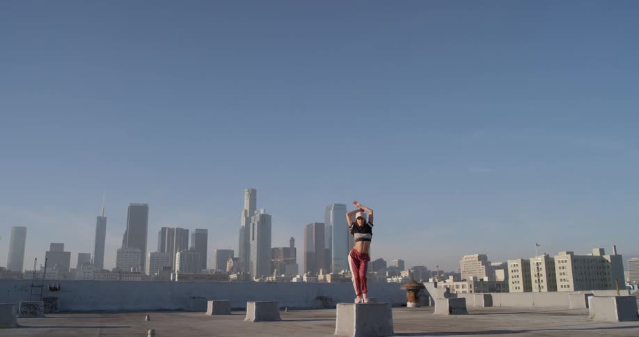 A woman dances on a building rooftop