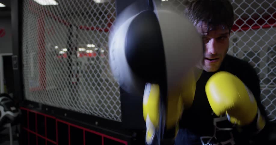The man is punching a speed bag in the gym