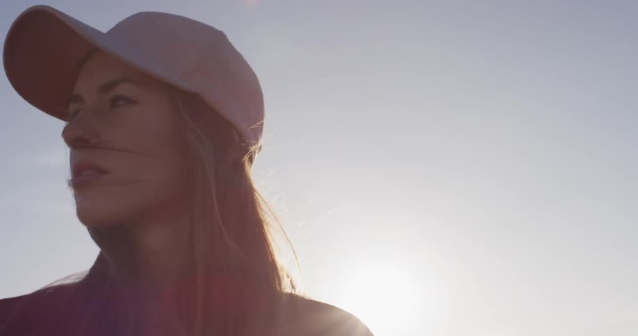 A woman in a pink hat stands outside in the sunshine