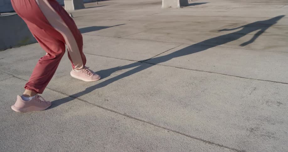 A woman in pink shoes dances on a rooftop