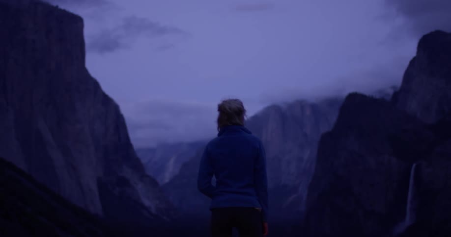 The woman looks out over the mountain range at dawn