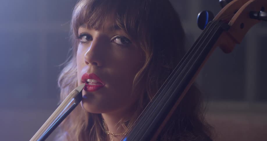 Woman sits holding a cello with a bow against her lop