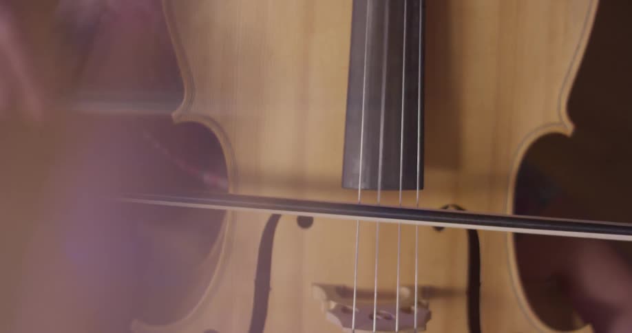 Person pushes a bow over cello strings